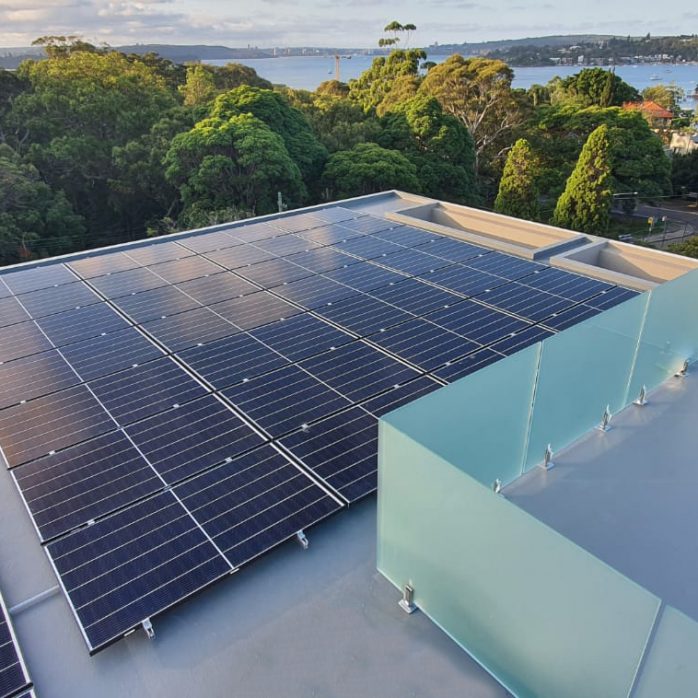 Top view of solar panel installed on the building surrounded by trees and a lake