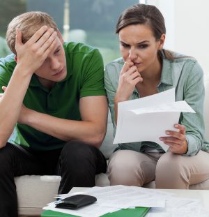 Worried young couple sitting on sofa and checking the bills